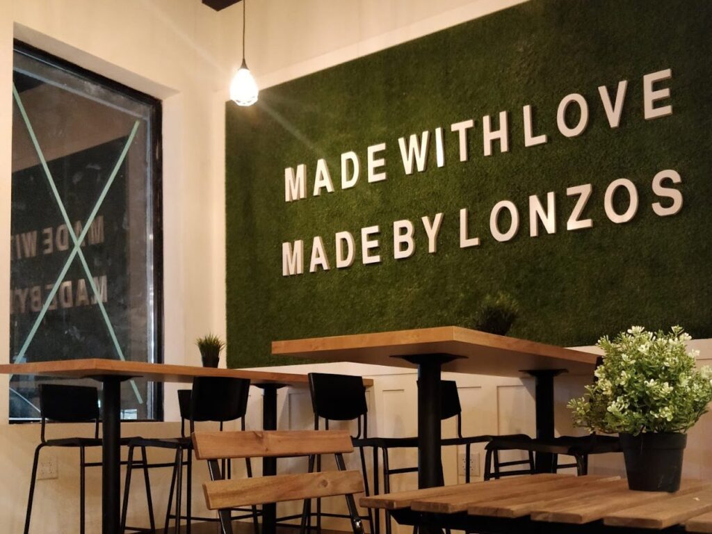 Inside Lonzo’s Scarborough: wooden tables in front of a green wall that reads Made with love, made by Lonzo’s